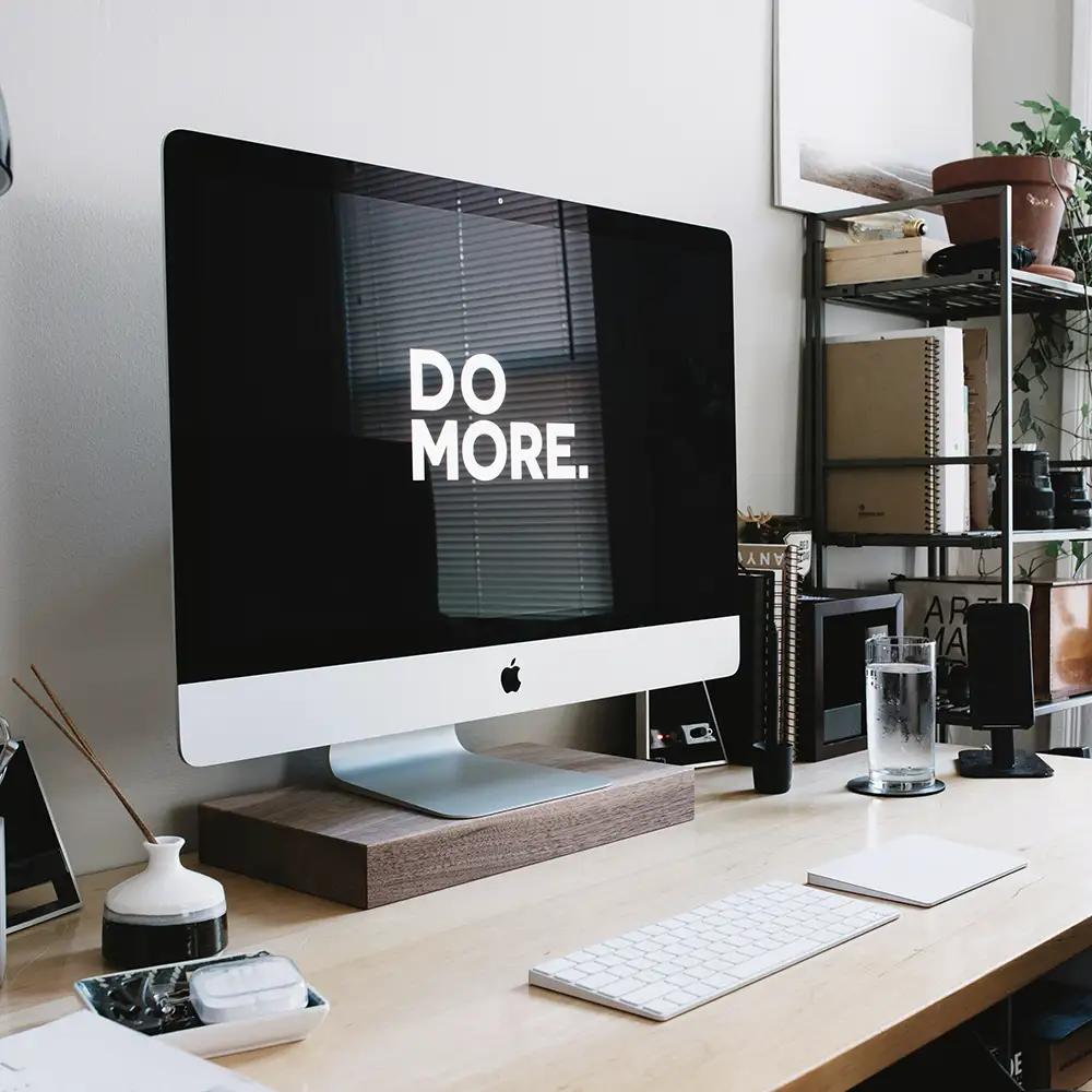 iMac auf aufgeräumtem Schreibtisch mit „DO MORE“ – Symbolbild für Suchmaschinenoptimierung und produktive Arbeit.